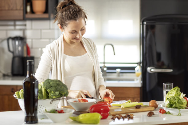 孕妇在厨房准备健康的素食和微笑图片下载