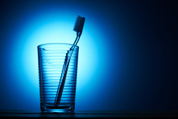 牙刷放在蓝色背景的饮水杯里图片下载