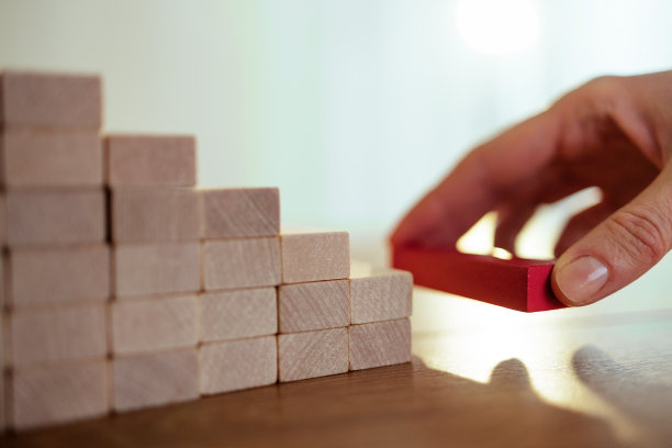 难以辨认的商业女性将木块放在塔的底部图片下载