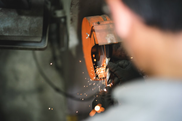 蓝领工人在砂轮机上磨钻头图片下载