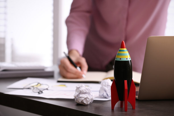 女人在凌乱的桌子上工作，专注于玩具火箭。创业的概念图片下载