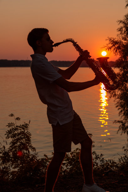 一个年轻人在傍晚日落时分吹萨克斯图片下载
