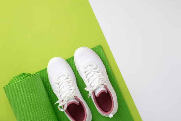健身器材的概念。俯视图照片白色运动鞋在瑜伽垫上的双色绿色和白色背景与空白图片下载