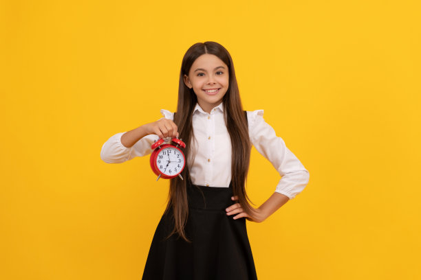 最后的机会。准时的少女检查时间。欢快的孩子带着闹钟。图片下载