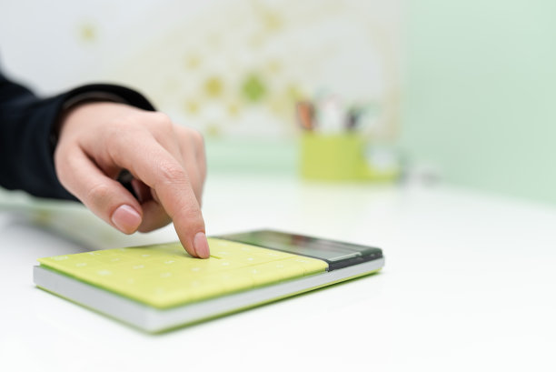 女商人指着桌面上的计算器和笔记本。用记事本按压桌子底部的女人。显示最近的信息。图片下载