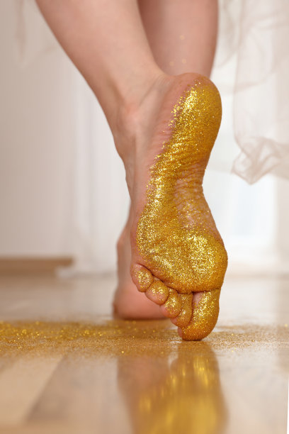 女性光脚上的金色闪光。享受生活，在世界上留下你的印记。图片下载