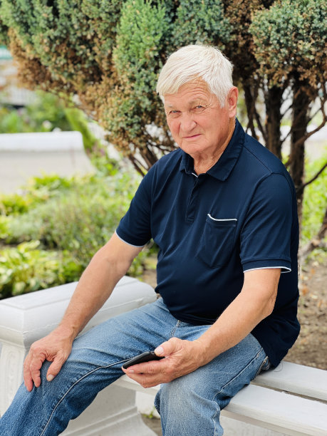 一位身穿蓝色polo衫、头发花白的老人看着镜头微笑。图片下载