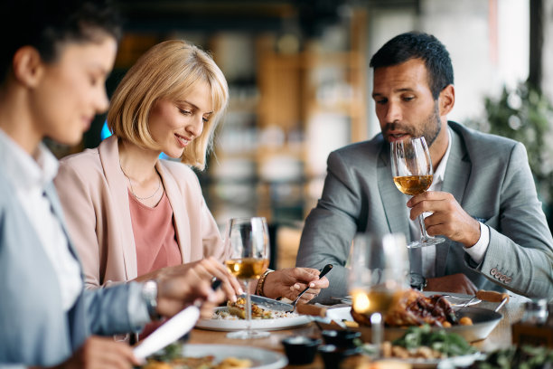 微笑的女商人一边吃饭一边和同事在餐厅吃午饭。图片下载