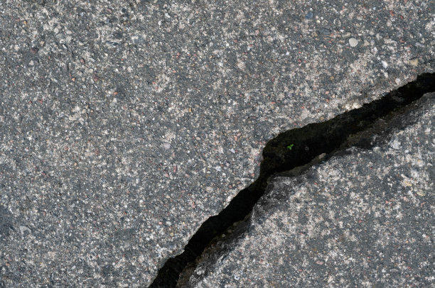 老旧风化裂灰黑色柏油路纹理图案，大细节破坏纹理沥青肮脏的背景平坦铺设，微小的绿叶，芽，芽，水平粗粒破碎图案宏观特写垃圾复制空间图片下载