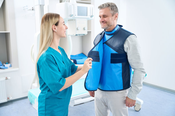 穿蓝色制服的医生给一个人穿上了防护服图片下载