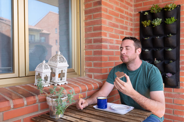 一名男子在自家阳台享用蛋糕。夏季休闲的生活方式。图片下载