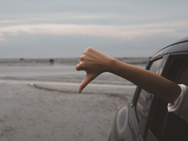 一个站在车外的女孩的手，大拇指朝下图片下载
