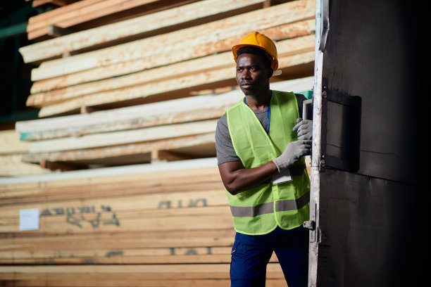 年轻的黑人工人正在关上木材仓库的门。图片下载