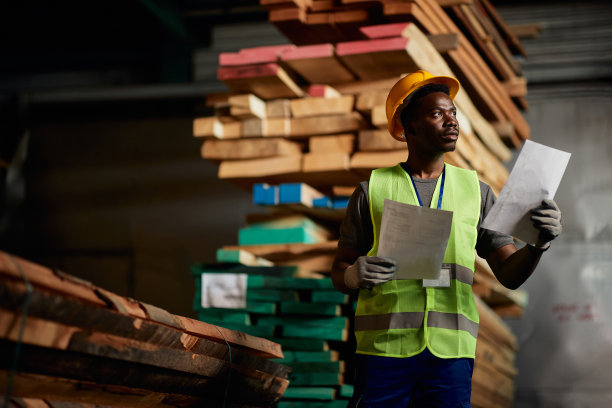 黑人工人一边在木材仓库工作一边分析装运计划。图片下载