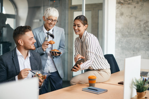 快乐的同事在办公室休息的时候用智能手机玩得很开心。图片下载