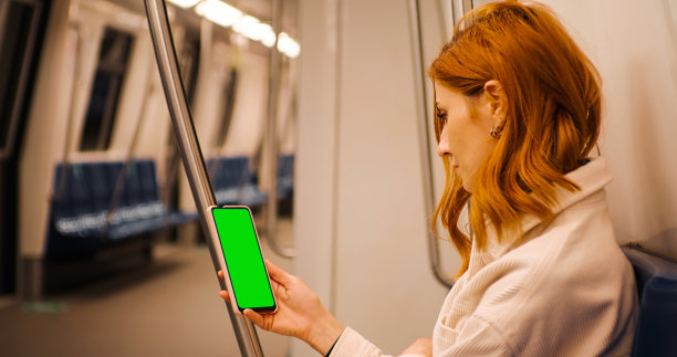 在地铁列车上看绿屏手机的女性。图片下载