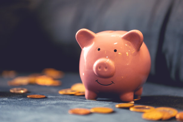 蓝色沙发上放着一个储蓄罐和硬币。家庭财政的概念。图片下载