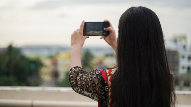 美丽的印度女人用她的手机相机拍照，年轻的亚洲女性摄影师图片下载