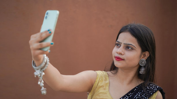美丽的印度女孩在户外用她的手机自拍，穿着传统服装的开朗的亚洲女人点击自拍图片下载