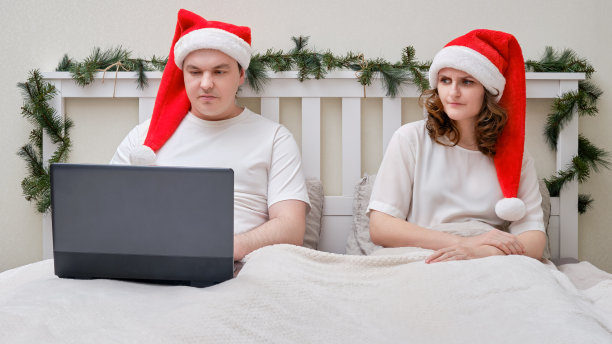 一个女人因为加班不开心，在除夕把一张床装饰成圣诞用，一家人夫妻在家里的卧室里图片下载