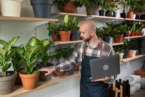 一名白人企业家在花店用笔记本电脑查看商店库存，然后对着镜头露出大大的微笑图片下载