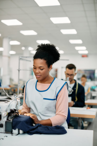 年轻的黑人妇女在纺织厂做裁缝。图片下载