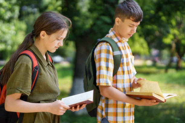 在城市公园里的学生肖像，十几岁的学童一个男孩和一个女孩走在穿过公园的小路上，阅读书籍，教育和回到学校的概念图片下载
