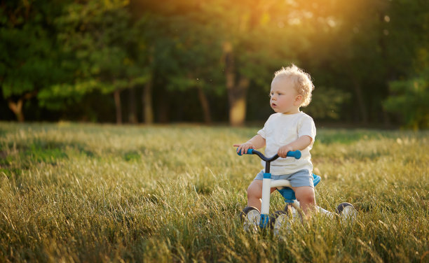 可爱宝宝学骑平衡自行车。一个小孩试图在阳光明媚的公园里骑自行车。那孩子梦想成为一名摩托车手图片下载