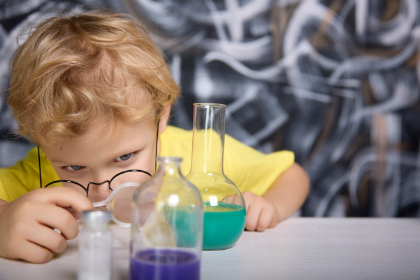 男孩用放大镜仔细观察玻璃管里的蓝色液体图片下载