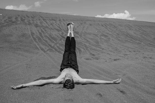 孤独的人躺在沙滩上，双腿直立在沙漠里图片下载