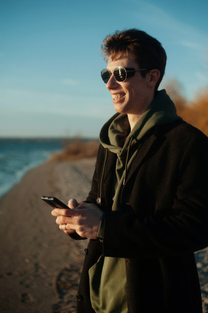 一个年轻人在海滩上打电话图片下载