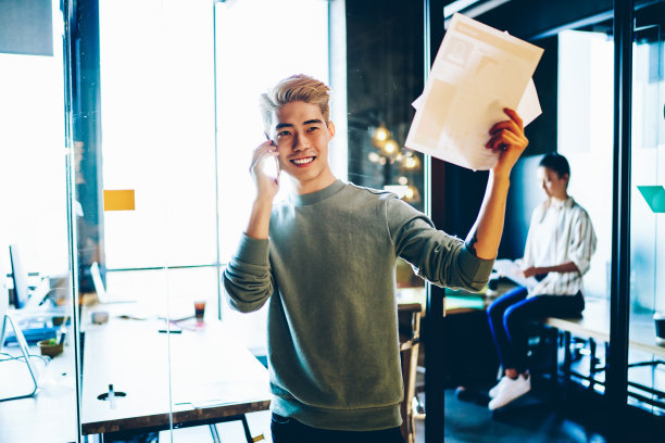 快乐的日本潮男喜欢用智能手机和同事聊天，连接4g无线网络，快乐的中国男性用现代手机上的应用程序在线通话图片下载