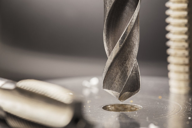 金属钻头用刨花在工业钻床上的铝坯上打孔。金属加工行业。多刀和立铣刀。图片下载