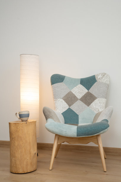 客厅的边桌上放着一杯咖啡，旁边是一把斯堪的纳维亚式的扶手椅，有落地灯照明。图片下载