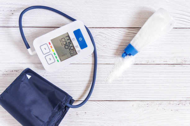 血压计放在木桌上，还有盐和糖果。动脉高血压。图片下载