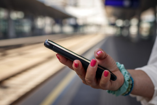 在火车站，女性手里拿着手机图片下载