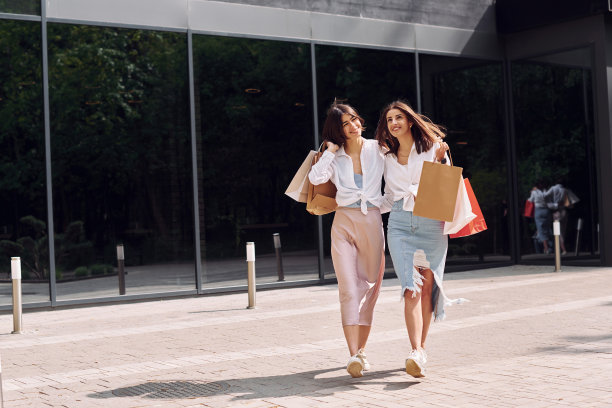 快乐的买家。两个女性朋友有一个购物日。带着袋子在户外散步图片下载