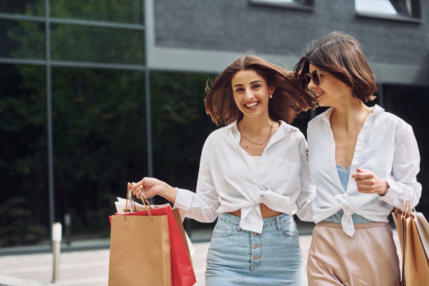 两个女性朋友有一个购物日。带着袋子在户外散步图片下载