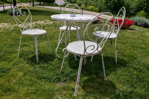 一张有四把椅子的咖啡圆桌，草地上漆成白色的锻铁花园家具，意大利图片下载