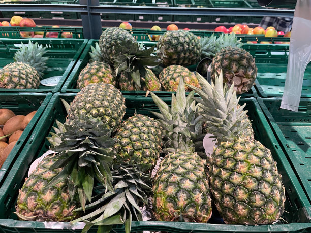 新鲜菠萝装在超市的绿色塑料包装盒里。蔬菜店图片下载