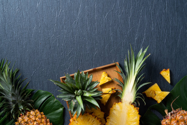 新鲜切下的菠萝，带热带树叶，深蓝色背景。图片下载
