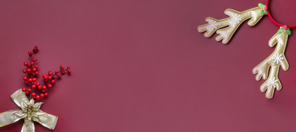 背景横幅为圣诞节和新年。圣诞装饰品，红色背景上的红色浆果和圣诞鹿角。空出文本空间。图片下载