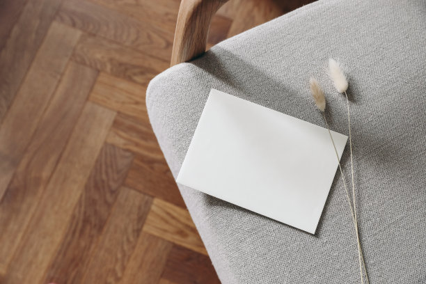 波西米亚中性文具静物场景。空白贺卡，邀请函模型。亚麻家具上的干兔尾草。优雅的中世纪扶手椅。模糊的木地板。前视图。图片下载