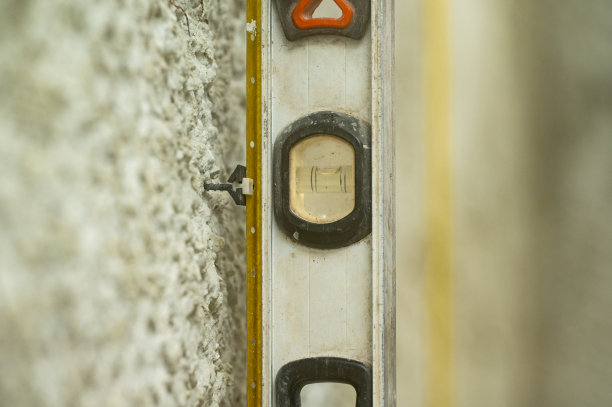 一名男子在检查安装的指标灯是否与水平仪一致，检查施工水平。图片下载