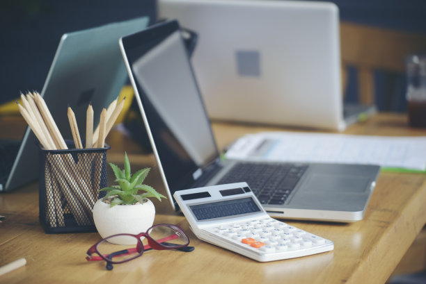 家庭办公办公桌概念。笔记本电脑，总结报告，图表和计算器，会计或会计计划年度预算和税收。电脑、计算器和铅笔放在木桌上，在家工作图片下载