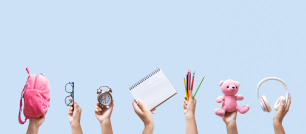 横幅与学校文具在女性手中的蓝色背景与复制空间。笔记本，背包，铅笔和彩色背景的其他工具图片下载