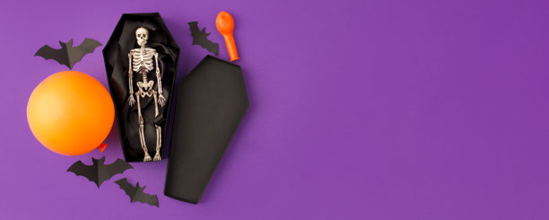 万圣节快乐的假期。万圣节的装饰品，黑蝙蝠、骷髅、棺材都是用鲜艳的紫色纸做背景。万圣节派对贺卡拷贝空间。欢迎横幅图片下载