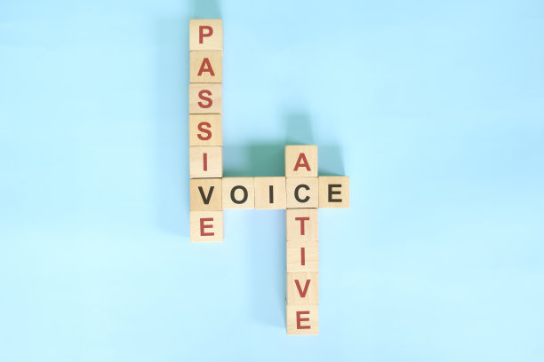 英语语法教学中的主动语态与被动语态话题。木制方块纵横字谜平躺在蓝色的背景。图片下载