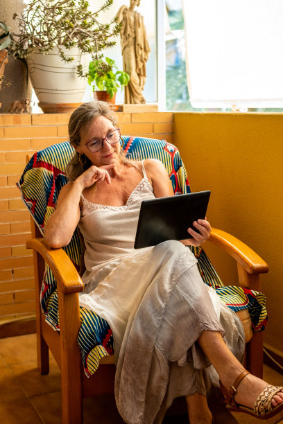 一个快乐而自信的女人在她客厅的平板电脑上咨询她的投资图片下载