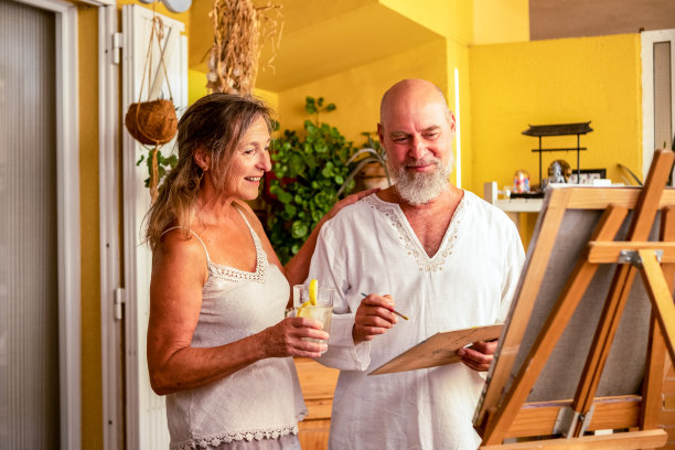 一对自信、快乐的老年夫妇在客厅里画画，享受着他们的闲暇时光和生活图片下载